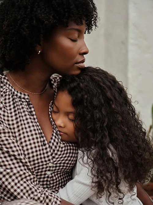 Mother and young child embracing closely.